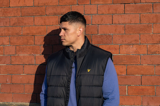 Plus size man wearing a black Lyle & Scott puffer jacket over a long sleeve blue polo shirt