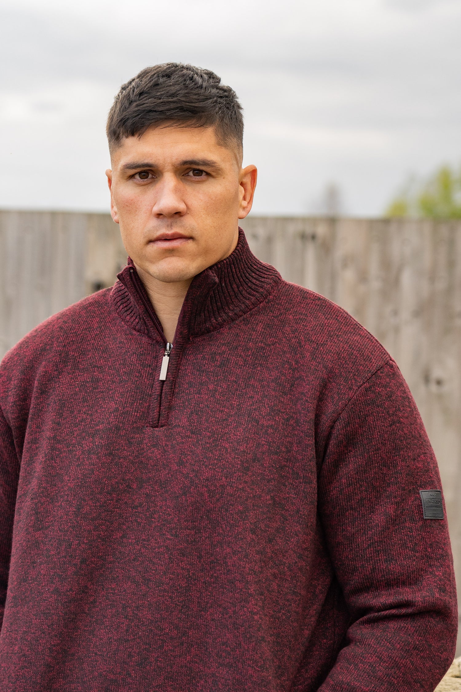 Man wearing a maroon pullover with a blurred background